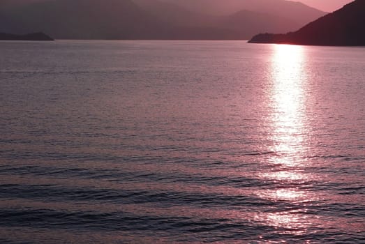 Mountain, ocean and water wave at sunset