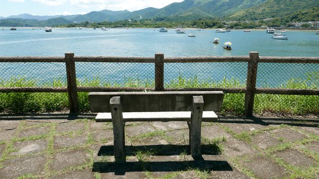 Outdoor wooden fence, bench, mountain and the motorboats