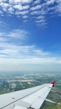 Vertical wing of airplane with green land and blue sky