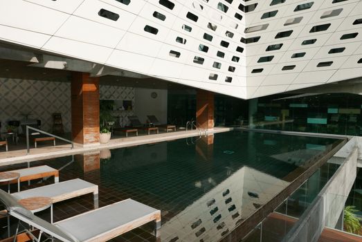 The swimming pool in the hotel with reflection suntan chair