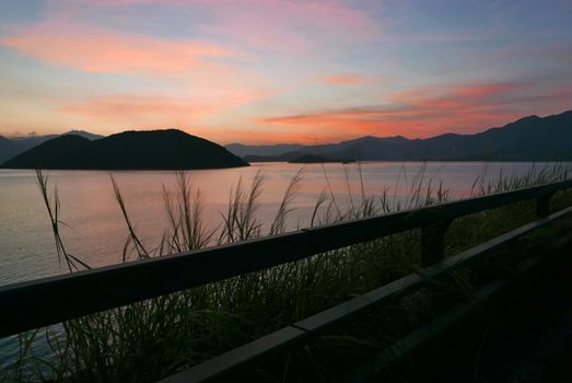 The Silhouette of mountain, plant, fence and ocean at sunset