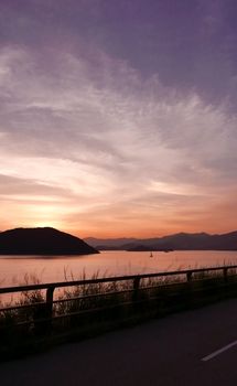 The silhouette of mountain, plant, fence, cloud and ocean at sunset