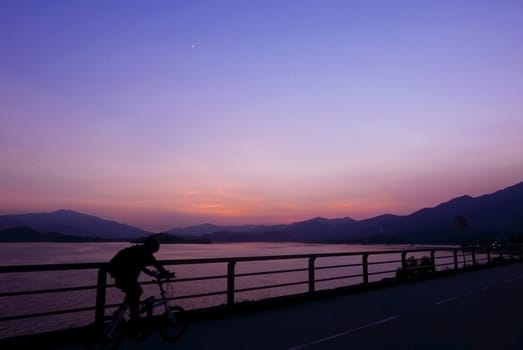 The silhouette of bicycle, fence and mountain with magical gradient purple sky