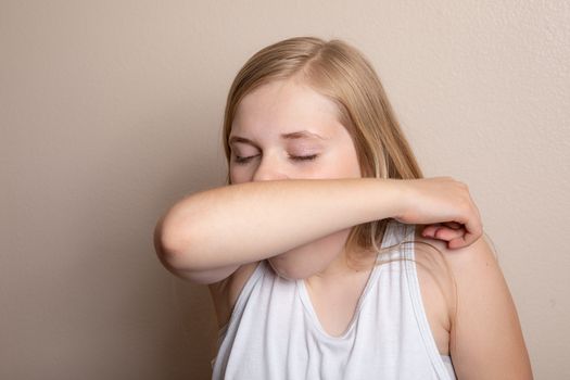 girl trying to prevent the spread of disease by coughing into her elbow