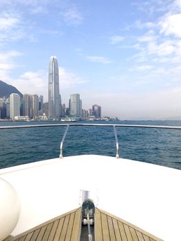 The head of white yacht and Hong Kong island in sunny day