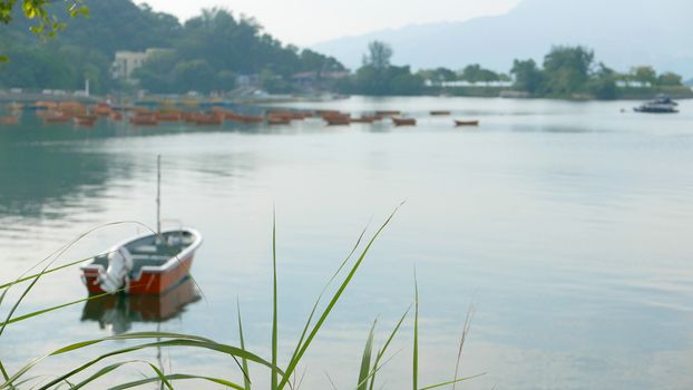 Red fishing boat on peaceful lake in day time