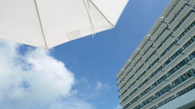 White suntanning umbrella and hotel building