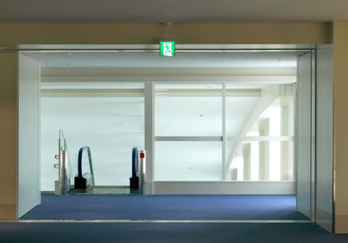 Building escalator with exit symbol light box and blue floor