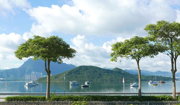 The mountain, recreational wooden boats, clouds, lake, blue sky and sun in Hong Kong