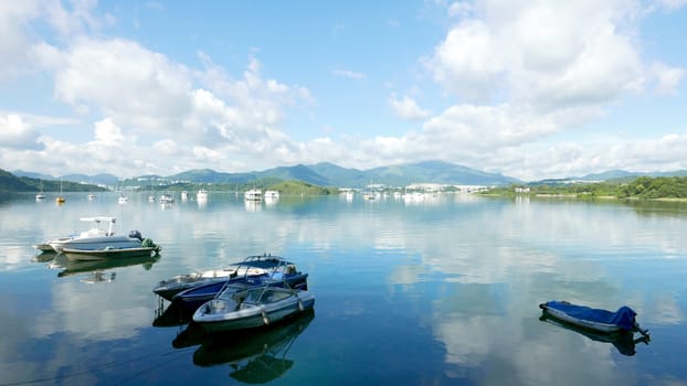 Boats, white clouds, lake and blue sky with reflection shadow