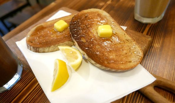 Breakfast butter lemon honey bread with cold drink on the wooden table