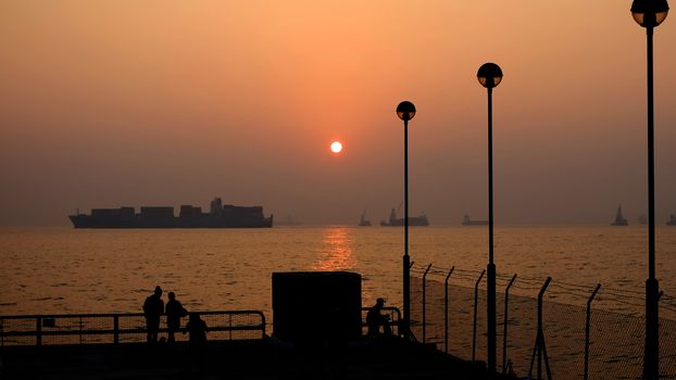 The silhouette of couple, street lamp and boat at sunset