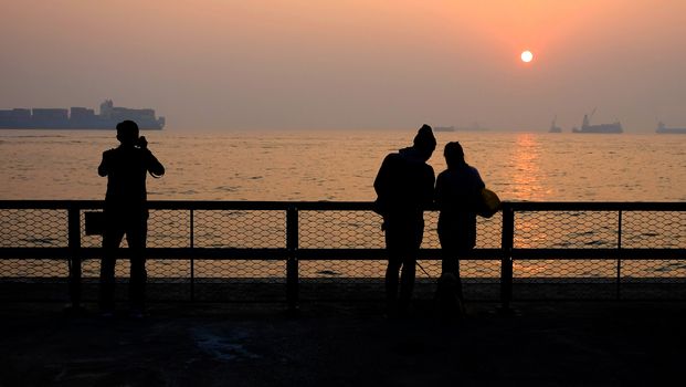 a couple of lovers are dating and a man is taking photos at sunset
