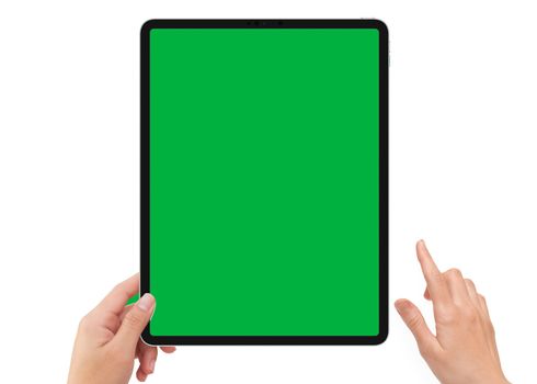 Isolated human left hand holding vertical black tablet media device with green screen for video production