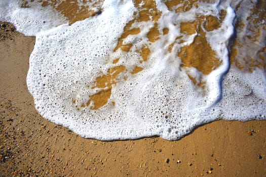 A small wave licking the sand at the beach