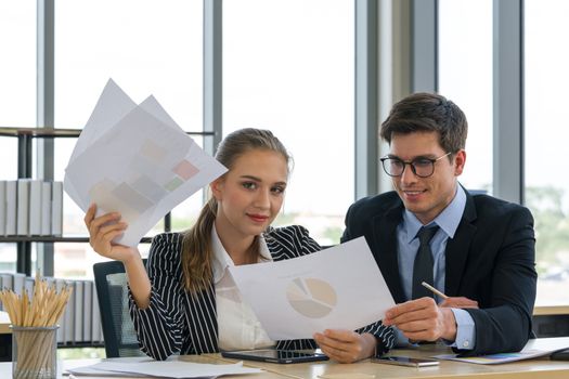 Morning work atmosphere In a modern office. Teen employees present annual profit and loss charts to colleagues. The man in the suit intended to read important data on paper.