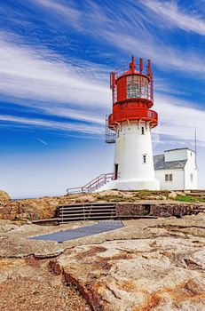 Historic red white lighthouse on the edge of rocky sea coast,  Lindesnes, South Norway