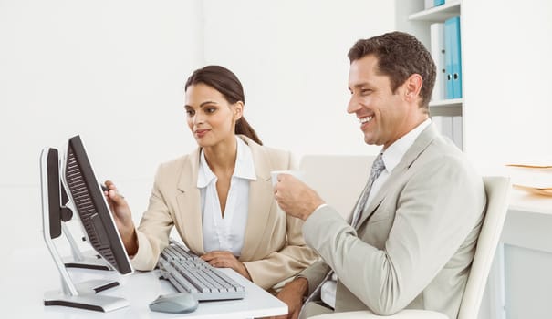 Two young business people using computer in office