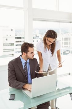 Two young business people using laptop in office