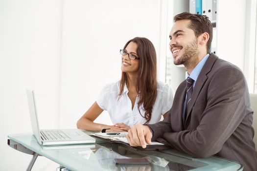 Two young business people using laptop in office