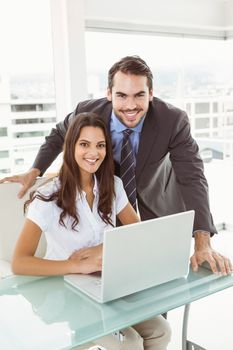 Portrait of two young business people using laptop in office