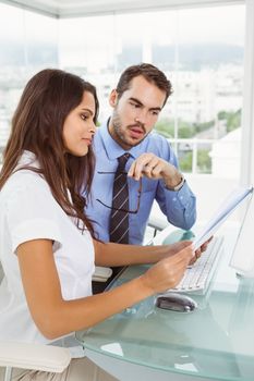 Two young business people using digital tablet in office