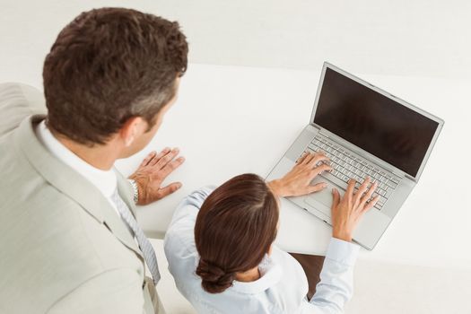Two young business people using laptop in office