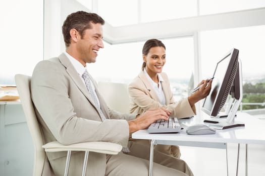 Two young business people using computer in office