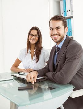 Portrait of two smiling young business people at office desk