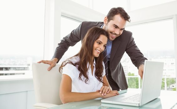 Two young business people using laptop in office