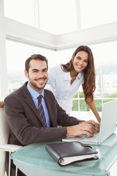 Portrait of two young business people using laptop in office