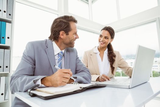 \Two young business people with laptop and diary at office