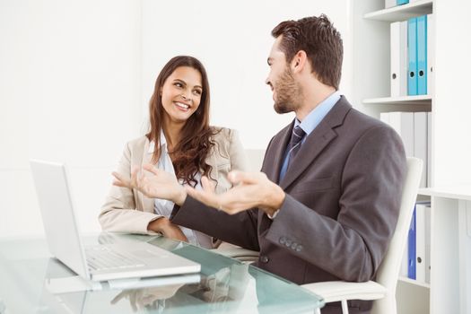 Two young business people using laptop in office