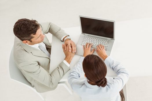 Two young business people using laptop in office