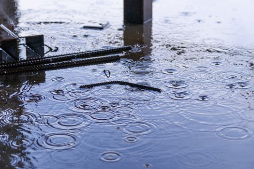 Rain drops and water on concrete with sky reflection in water