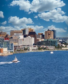 A tugboat sailing past the city of Halifax, Nova Scotia in blue water