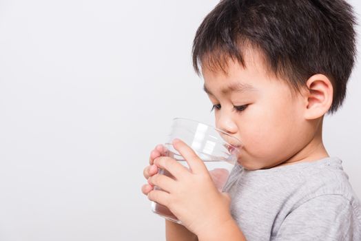 Closeup Asian face, Little children boy drinking water from glass on white background with copy space, health medical care