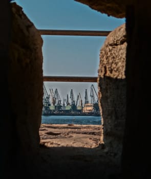 An industrial landscape at the coast of the sea, caught through a stone hole.