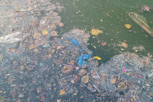Grease and plastic waste floating on the surface of the water caused by the littering of urban areas causing pollution and flooding caused by clogging the drainage.