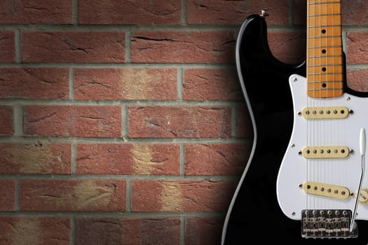A retro black and white electric guitar on brick background with copy space