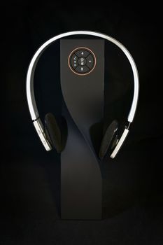 speaker and wireless headphones on black background