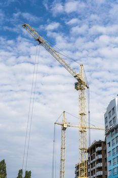 Crane and building under construction against blue cloudy sky