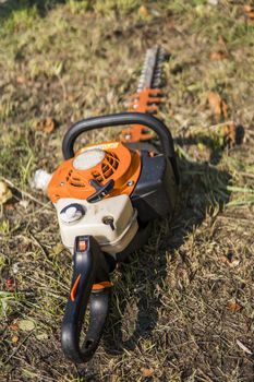 Orange gasoline engine portable chainsaw on a grass