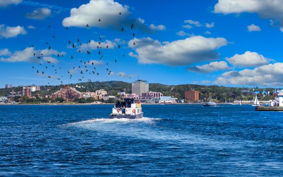 A full ferry pulling out of Halifax harbor and crossing blue water