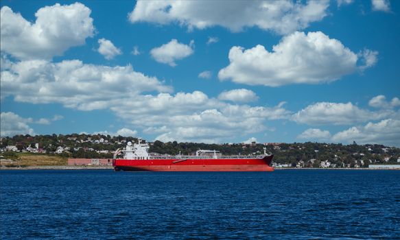 An empty red freighter in blue water of harbor