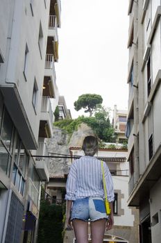 Young woman in a white shirt and with a yellow little bag tourist walking on the streent of Lloret de Mar in a beautiful summer day, Costa Brava, Catalonia, Spain. Streets of Europe