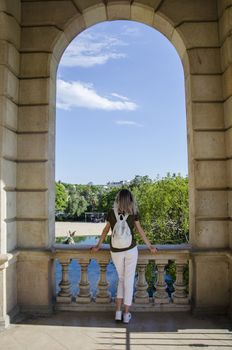 Amazing young wonam in greed t-shirt and white bag and pants looking on Fountain of Parc de la Ciutadella, in Barcelona, Spain. Park on the northeastern edge of Ciutat Vella, Catalonia