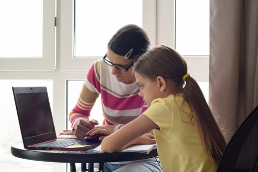 Mom and daughter are surfing the web together at home.