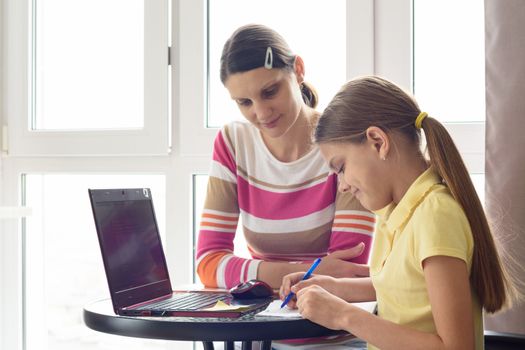 A tutor teaches a child at home, a girl writes in a notebook