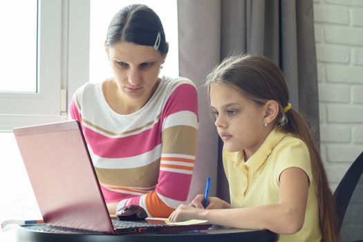 Mom and daughter solve homework using online distance learning